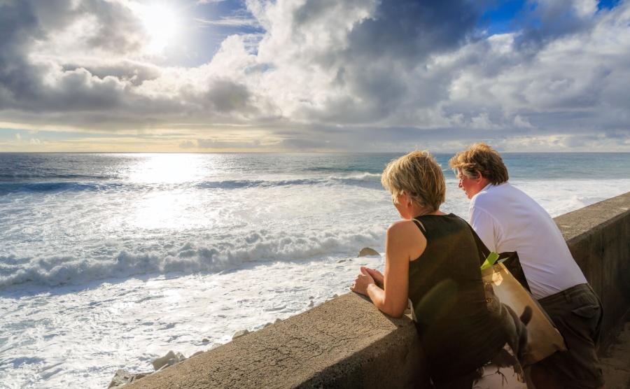 Senior tourists looking out over the Atlantic ocean in the afternoon at sunset, on the island Madeira in summer