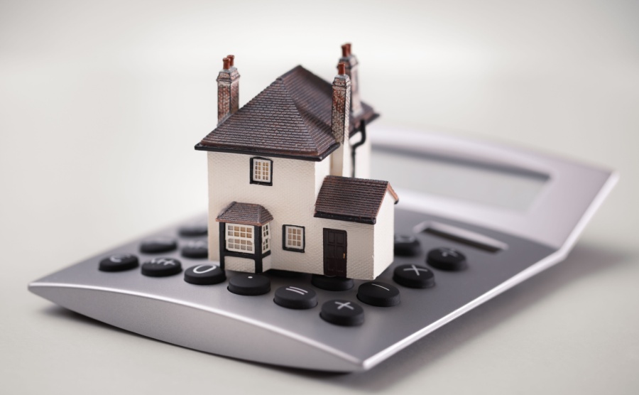 A house sitting on a calculator representing mortgage broker fees