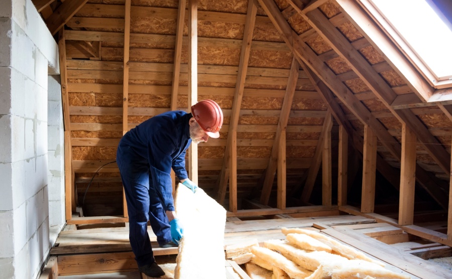 A builder laying insulation in a loft