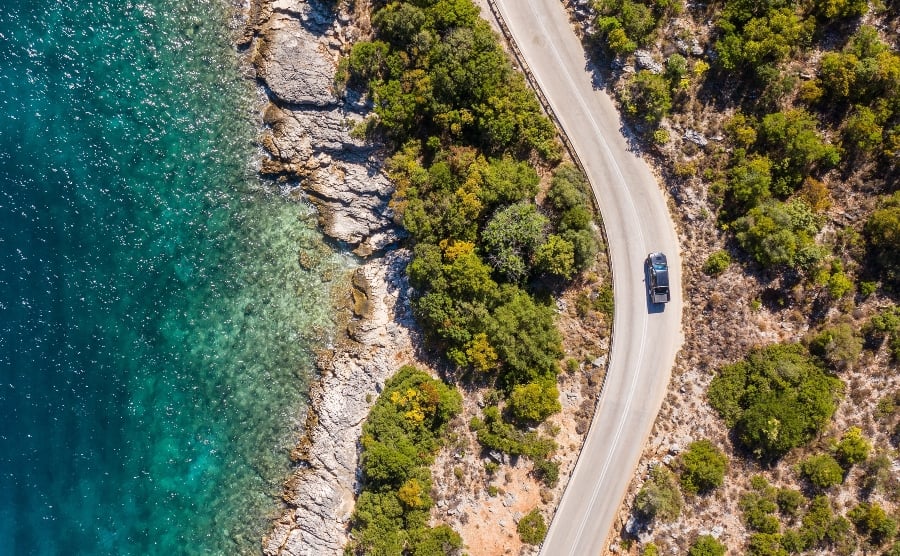 Aerial shot of car driving along coastal road in Greece