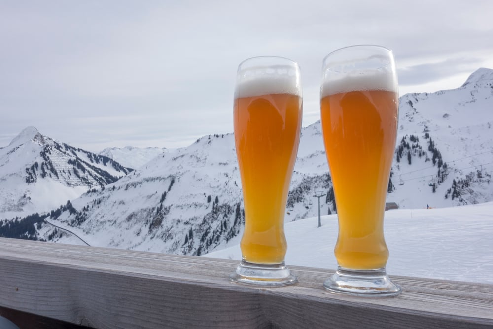 Two glasses of weizen beer at a ski area on a wooden fence