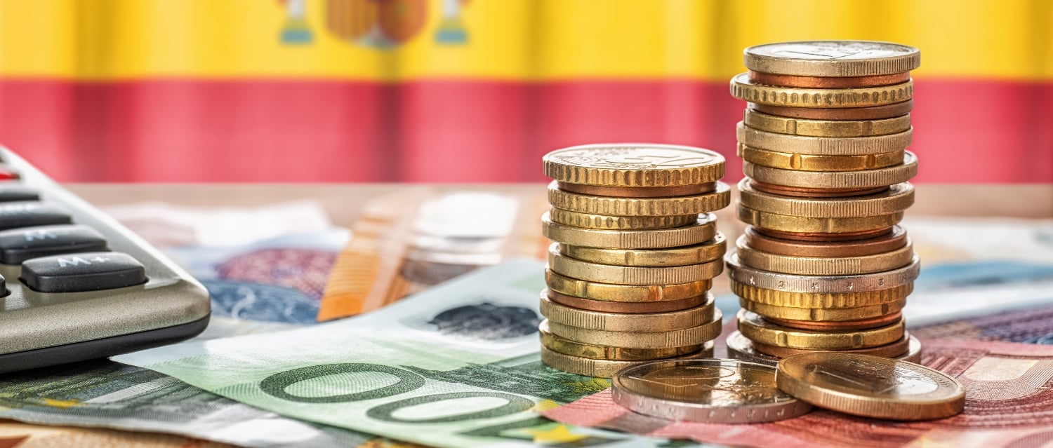 Euros and calculator in front of a Spanish flag