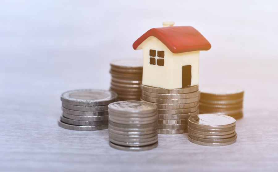 stacking coins and red roof house with the morning sunrise