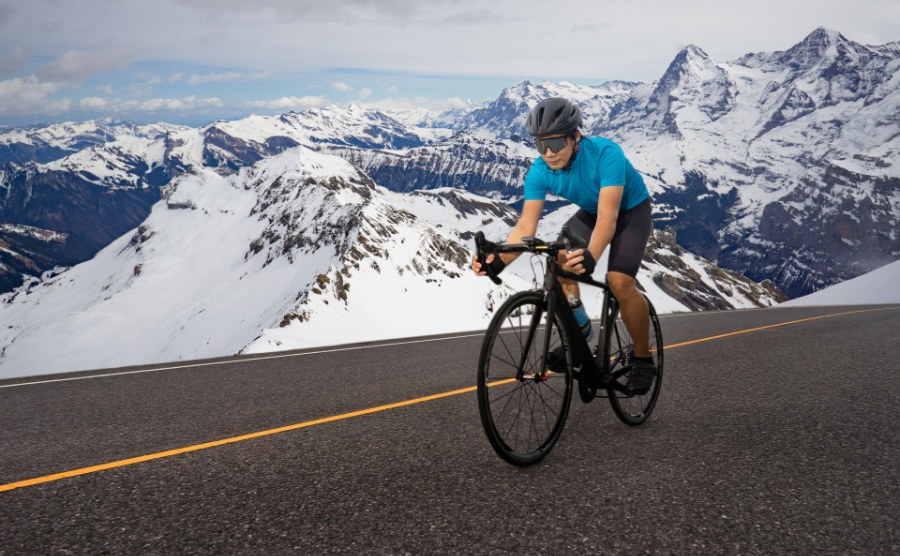 Cyclist on road bike cycles on asphalt in the Alps