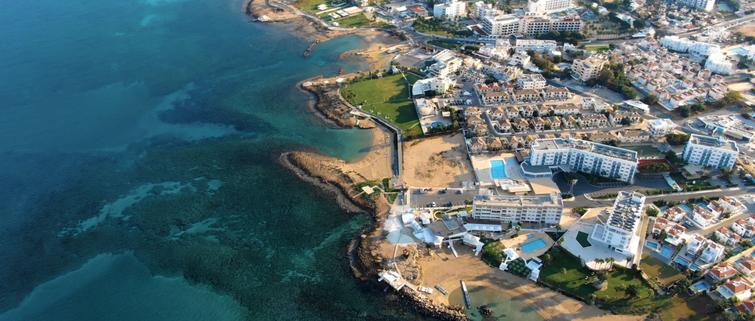 Drone shooting panorama of the coastline of the city with luxury hotels, villas, bays, ports with stylish yachts, sandy and rocky beaches and calm sea with clear blue water in Larnaca Cyprus.