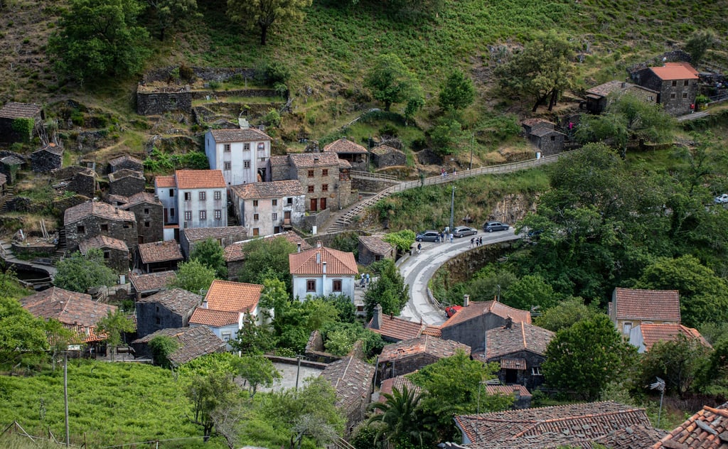 Affordable homes in Portugal, with dark schist houses and terracotta roofs on a steep green hillside in a Central Portugal village