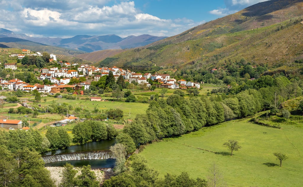 Affordable property area in Central Portugal, with white houses and terracotta roofs in a green river valley below mountains.