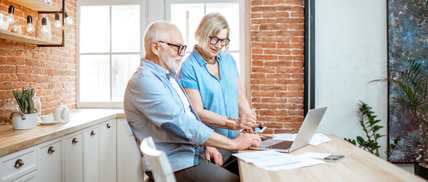 Senior couple looking at a laptop and paperwork