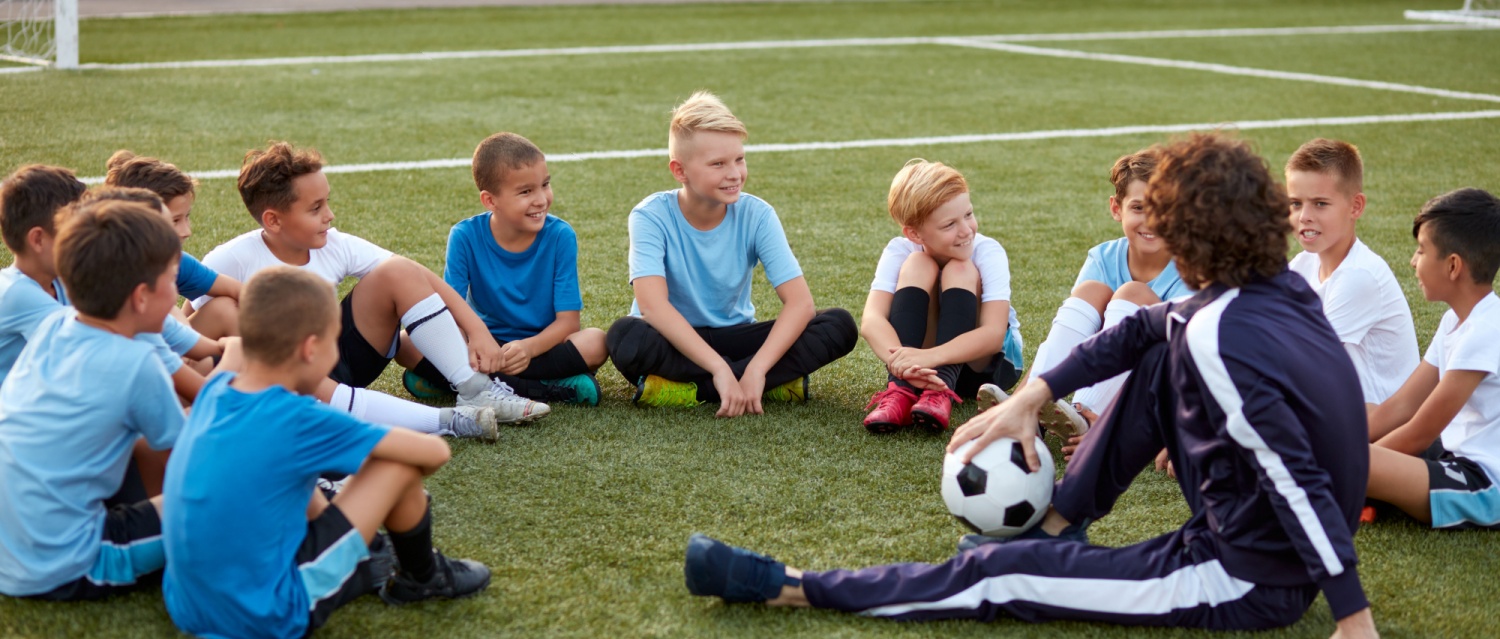 young team of sportive boys take a break during football competition, caucasian children talk, discuss, listen to trainer