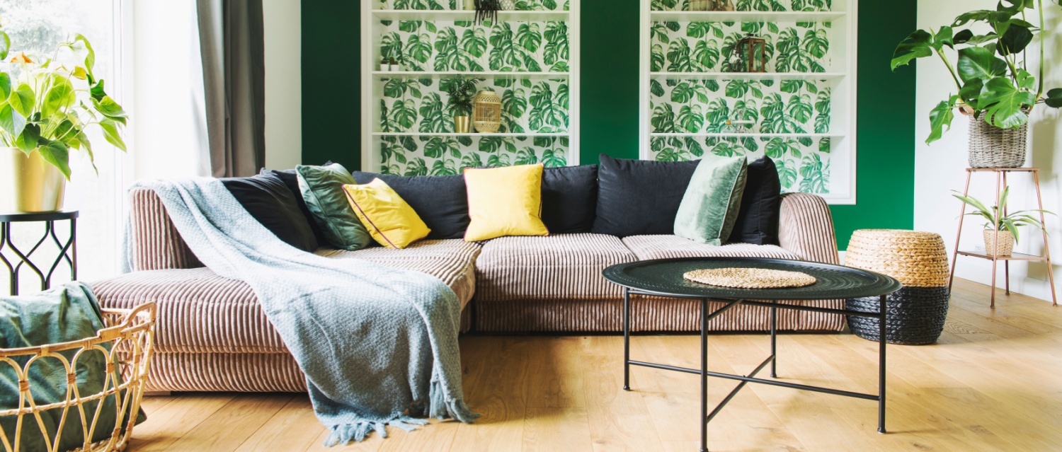 Modern and cozy living room with corduroy sofa, coffee table, plants and big window to the garden. Bright and sunny family space.