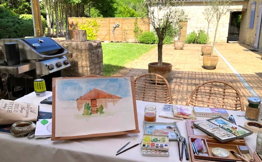 An artist works on their painting overlooking the view of their garden in France