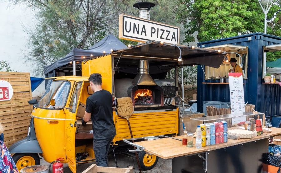 Man preparing pizzas to sell from a food truck