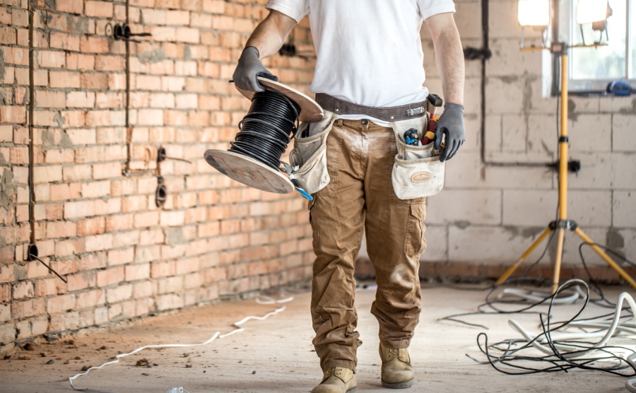 Electrician with tools, working on a construction site. Repair and handyman concept. House and house reconstruction.