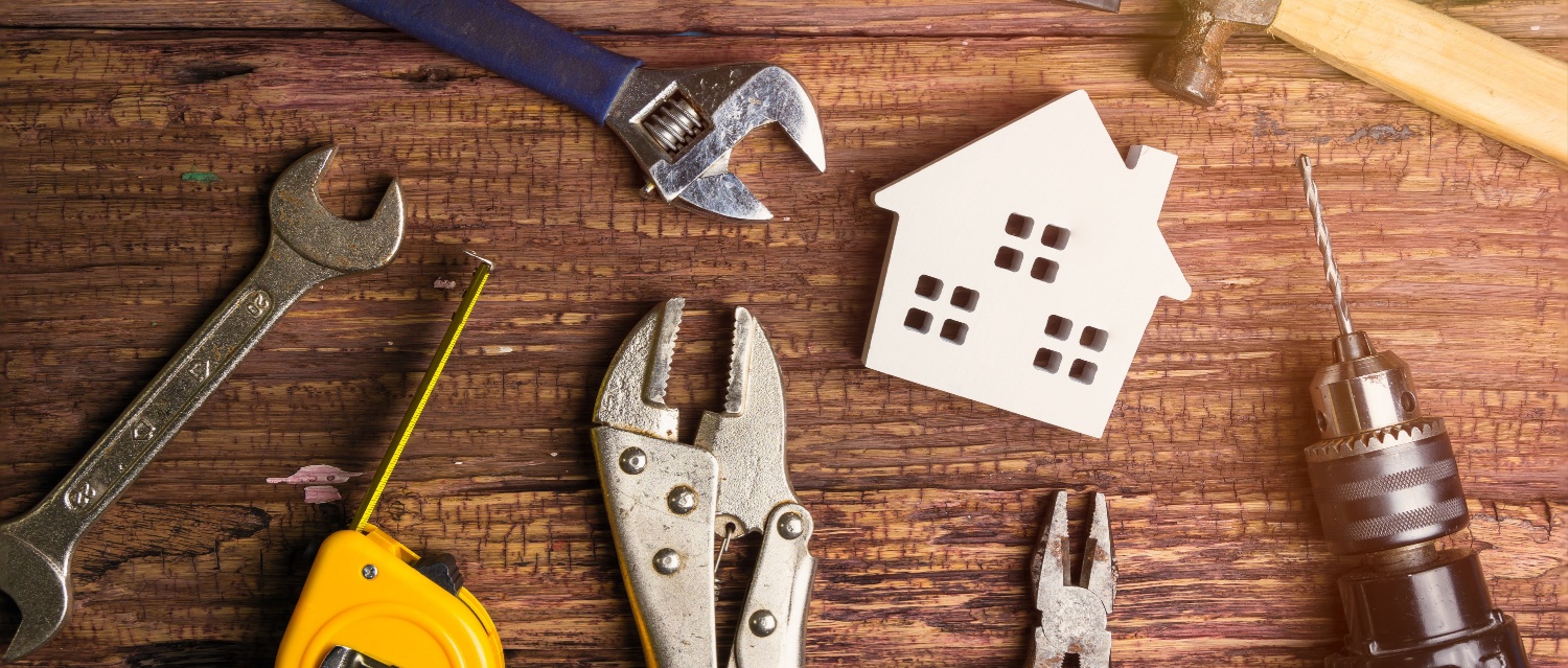Wooden white house toy and construction tools on wooden background with copy space.Real estate concept, New house concept, Finance loan business concept, Repair maintenance concept