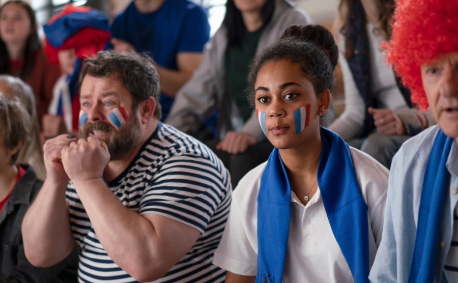 Worried football fans supporting French national team in live soccer match at stadium.