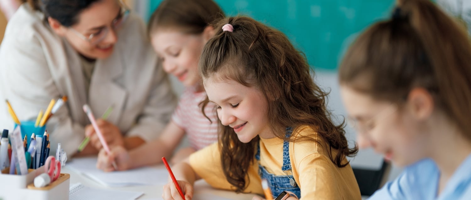 Smiling children writing with teacher