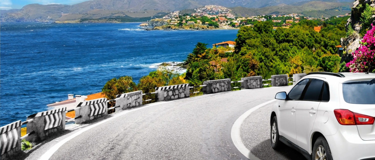 A white car drives by the road in mountains to the sea. Car trip and summer vacations background. Colorful seascape in the Mediterranean.