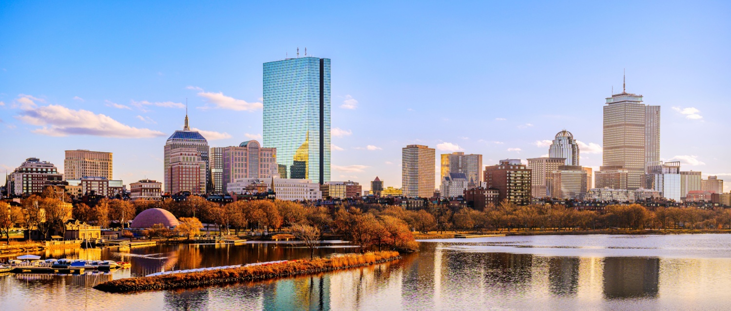 Boston City Skyline over the Charles River in Massachusetts, USA. A tranquil riverscape of Back Bay with golden illuminated wintery foliage in New England.