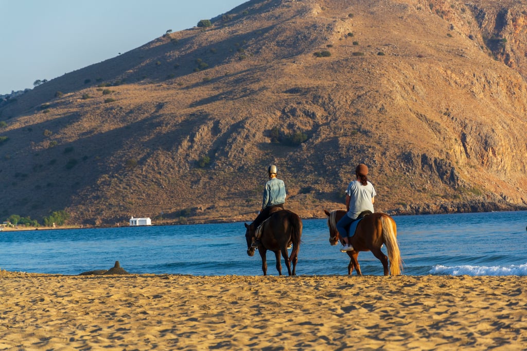 Man and woman riding horses on the beach