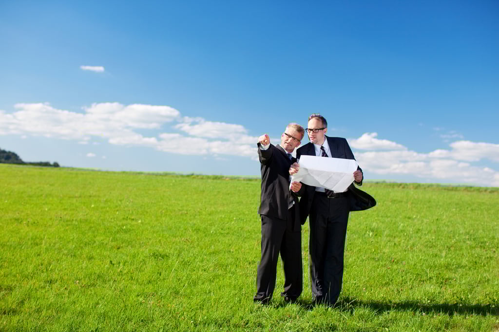 Men holding blueprint in a field