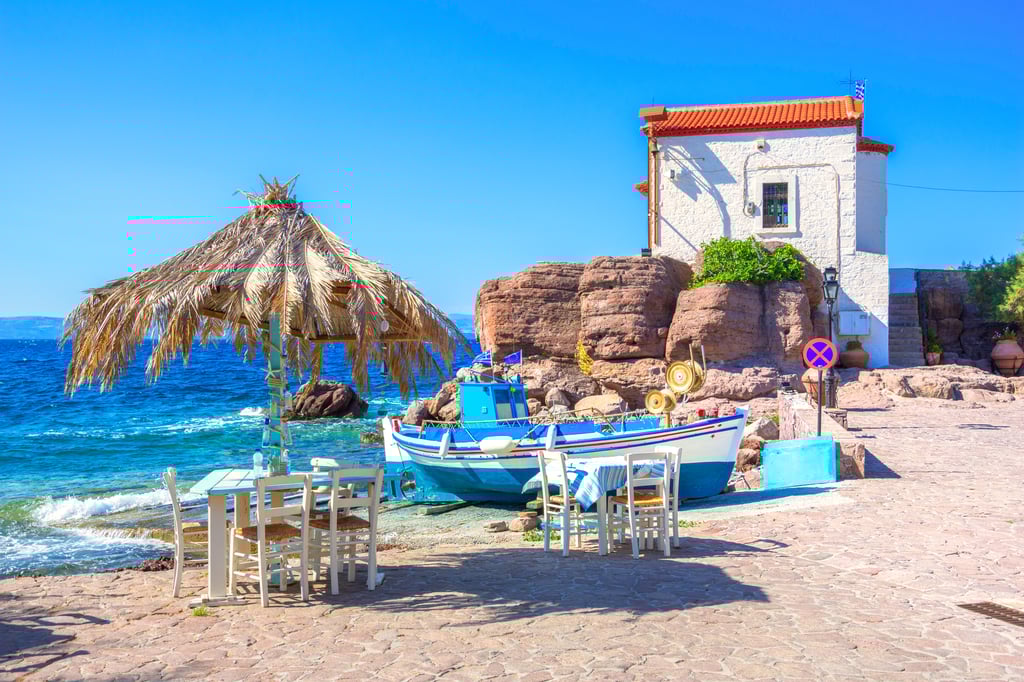 Church, boat and restaurant tables on a beach in Lesvos