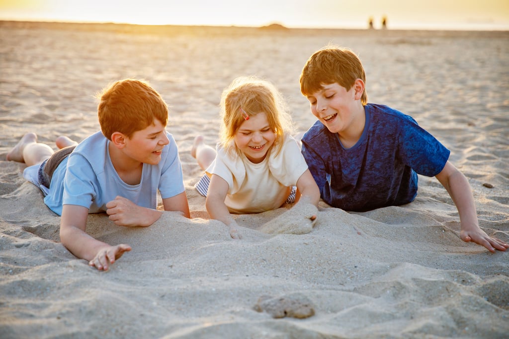 Two boys and girl playing in sand