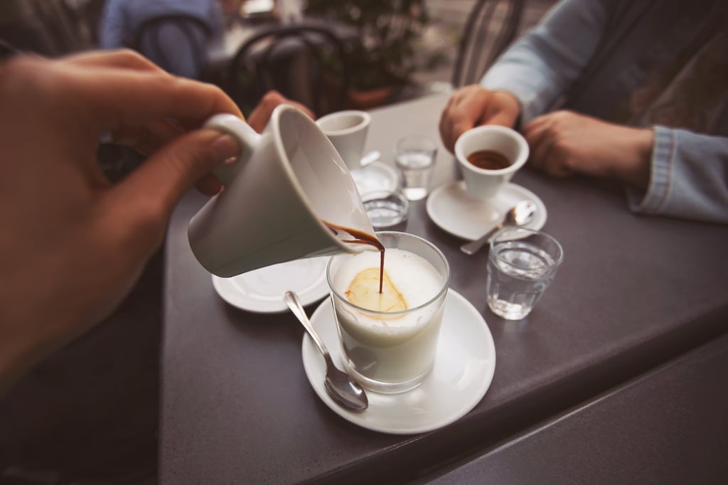 Coffee being poured into glass of milk