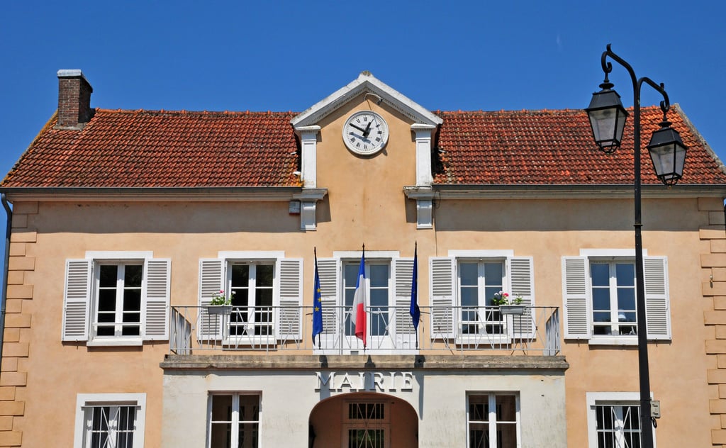 Traditional French village mairie building with tricolour flag, where planning applications are submitted