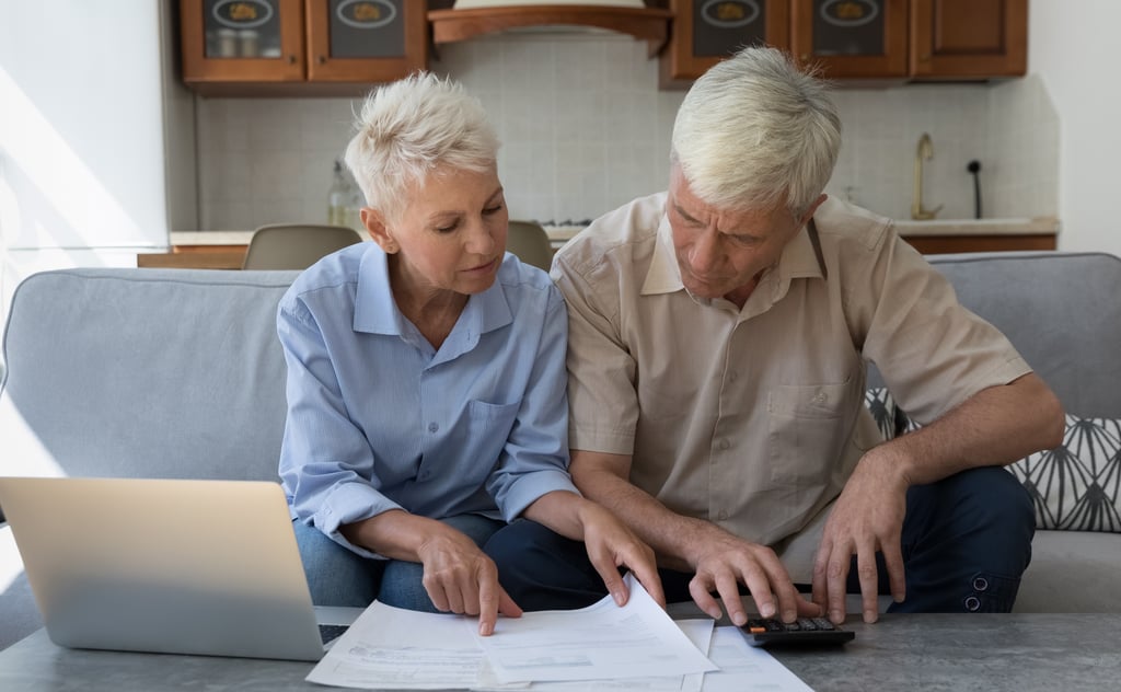 Couple reviewing financial documents and a laptop screen while planning their move to France