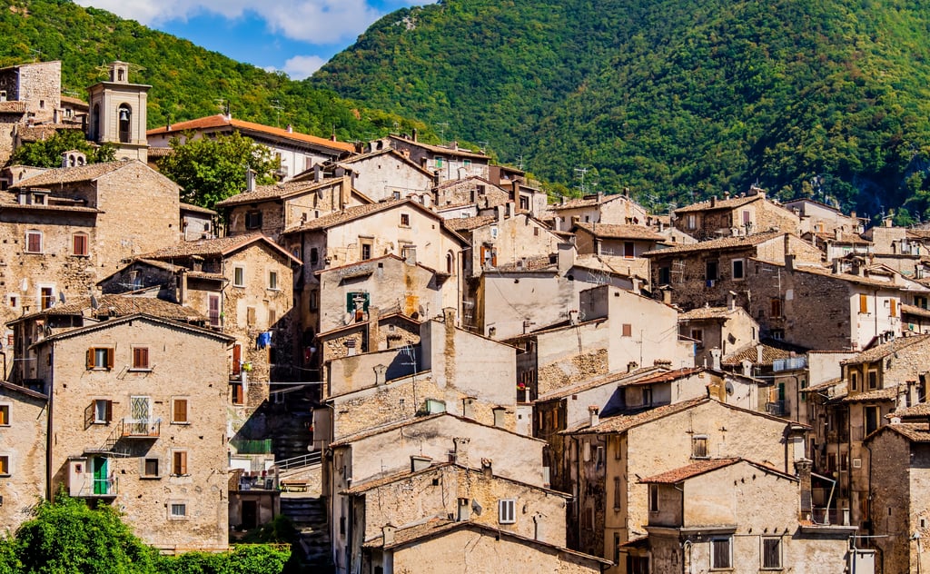 Stone village homes in Abruzzo with wooded hills behind, showing value-led places to live in Italy