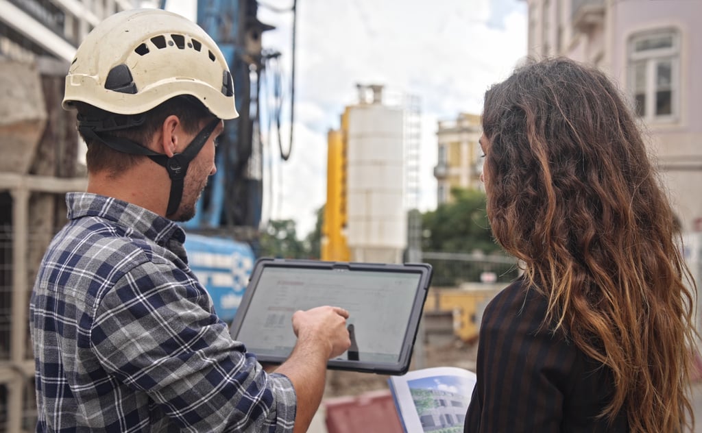 Builder and buyer review plans on site, showing why oversight matters when building property in Portugal.