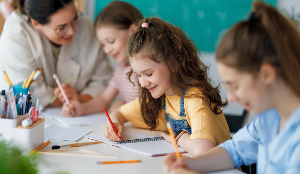 Smiling children writing with teacher