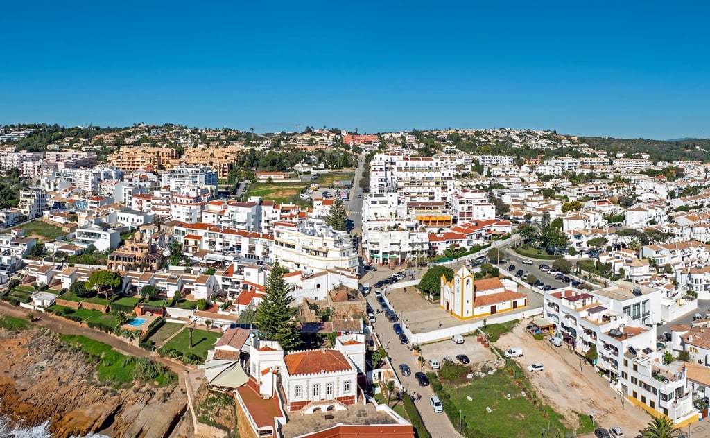 Aerial view of a whitewashed Algarve coastal town, where UK buyers weigh up buying property in Portugal in 2026