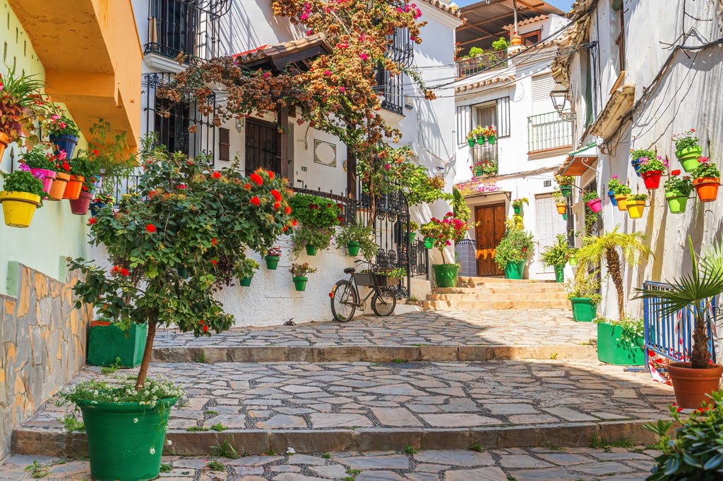 Whitewashed Andalusian street with potted flowers, a bicycle and stone steps, Estepona, Costa del Sol