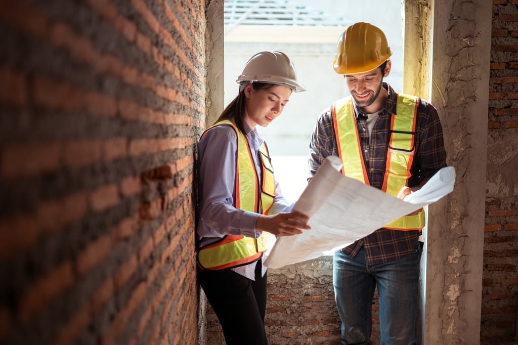 Architect and builder reviewing construction blueprints inside a brick property shell