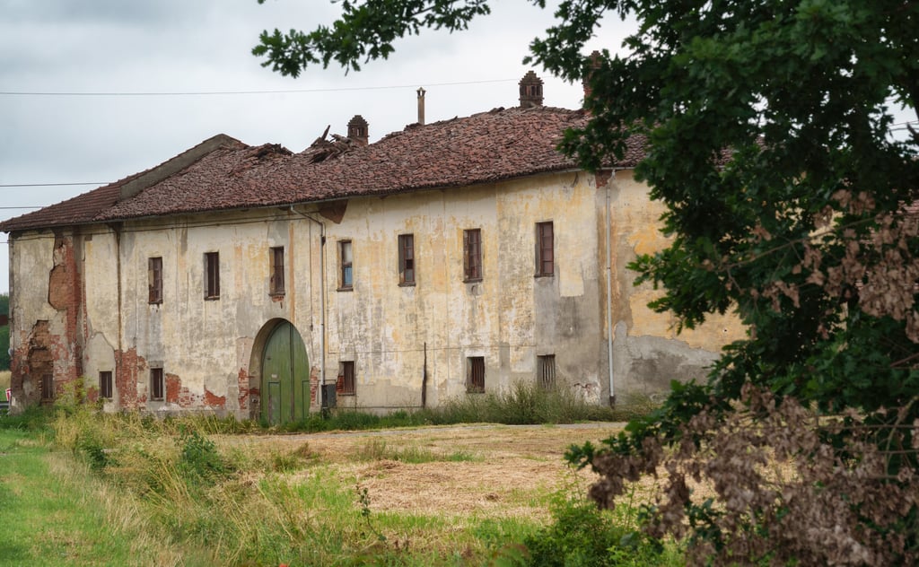Large rural house in Italy needing renovation, with weathered render, damaged roof tiles and original features