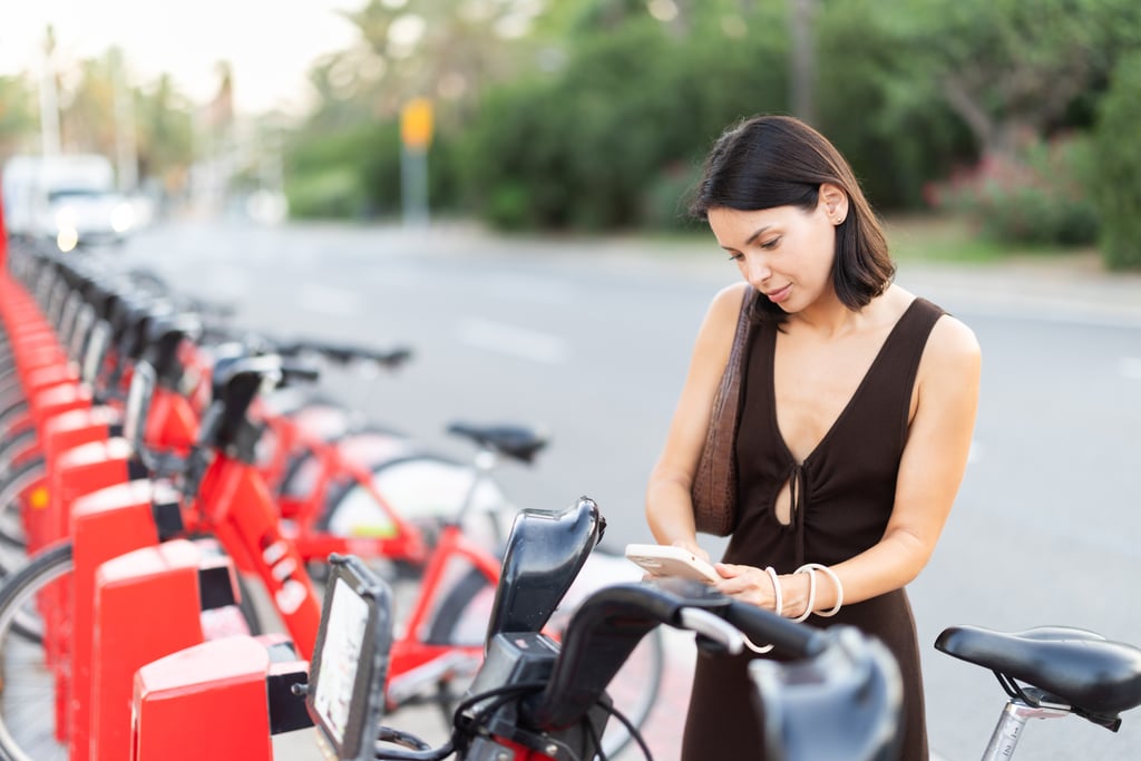 Woman uses a phone app to unlock a bike from a city bike-share station in Spain