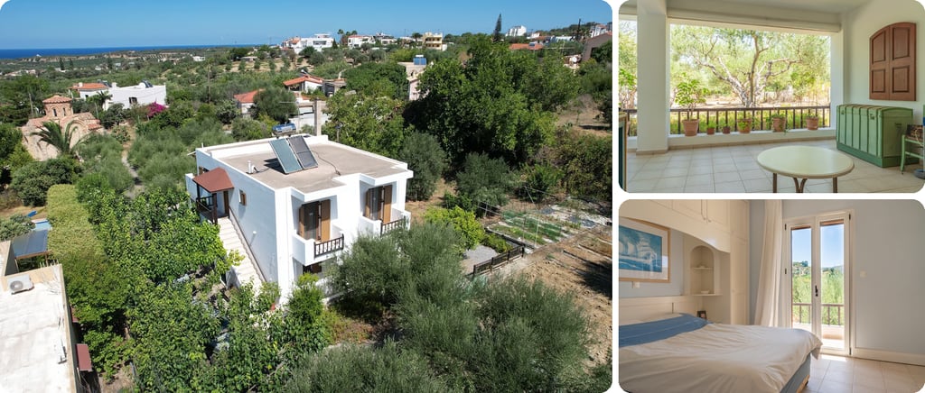 White two-storey house with a flat roof and solar panels among olive trees in Pigi, with the sea on the horizon