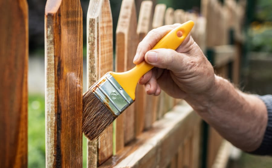 Man varnishing fence