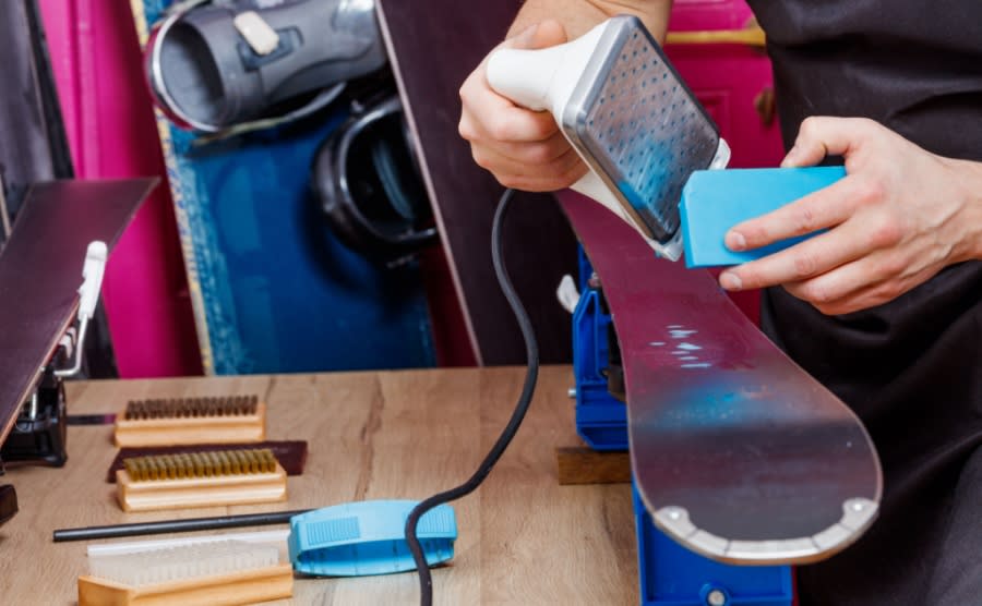 A worker applying wax to a set of skis