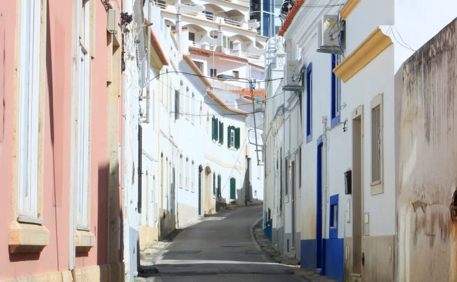Narrow cobblestone street in old town Albufeira showing condos in the background, Algarve, Portugal