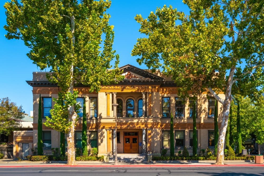 Old Chico City Hall, view from the street, the autumn landscape behind tall sycamore trees, Chico, Northern California