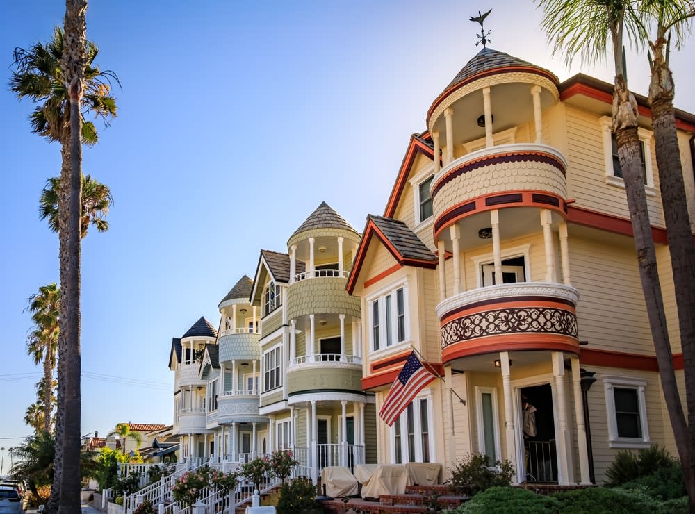 Ornate old Victorian houses on a street lined with palm trees in Huntington Beach, Orange County, California famous for surfing