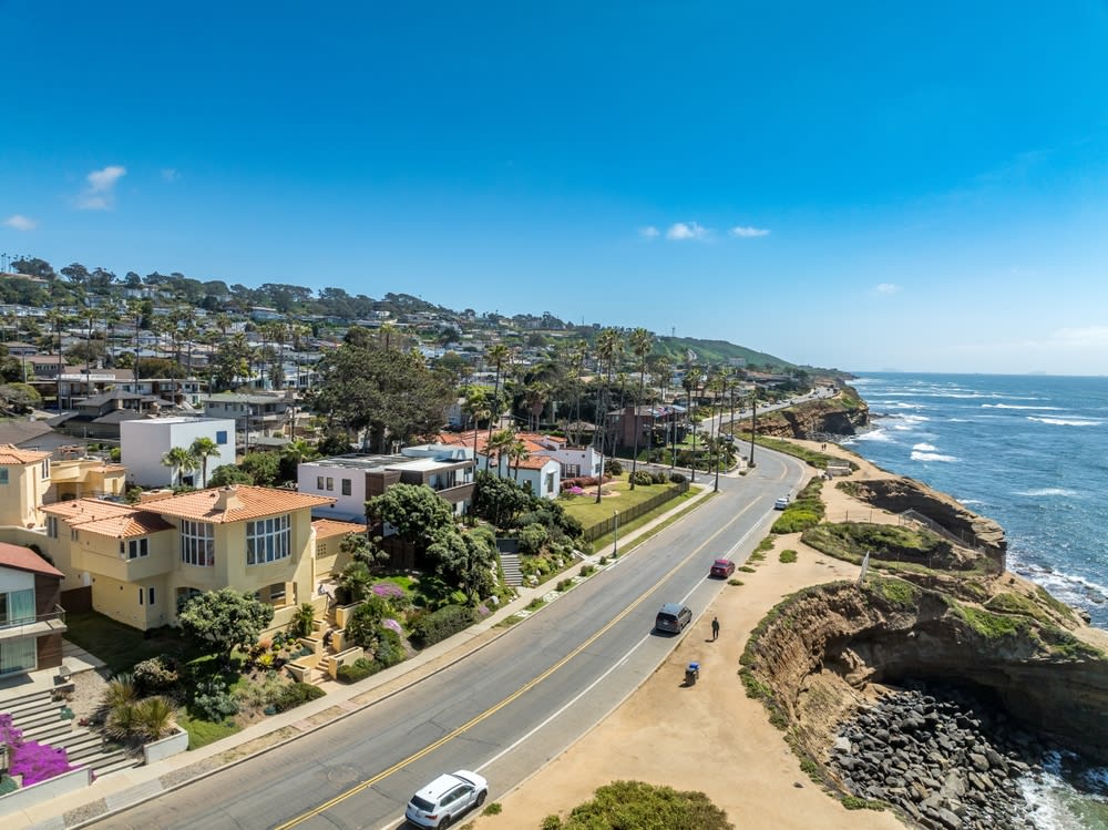 Aerial view of hillside luxury single family homes above Sunset Beach San Diego with palm trees and large terrace