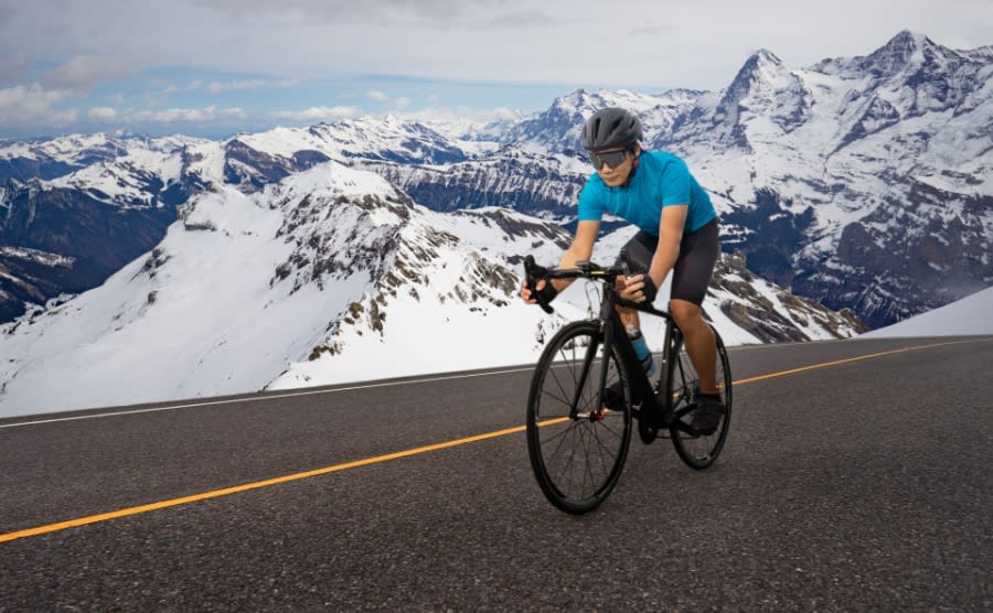 Cyclist on road bike cycles on asphalt in the Alps 