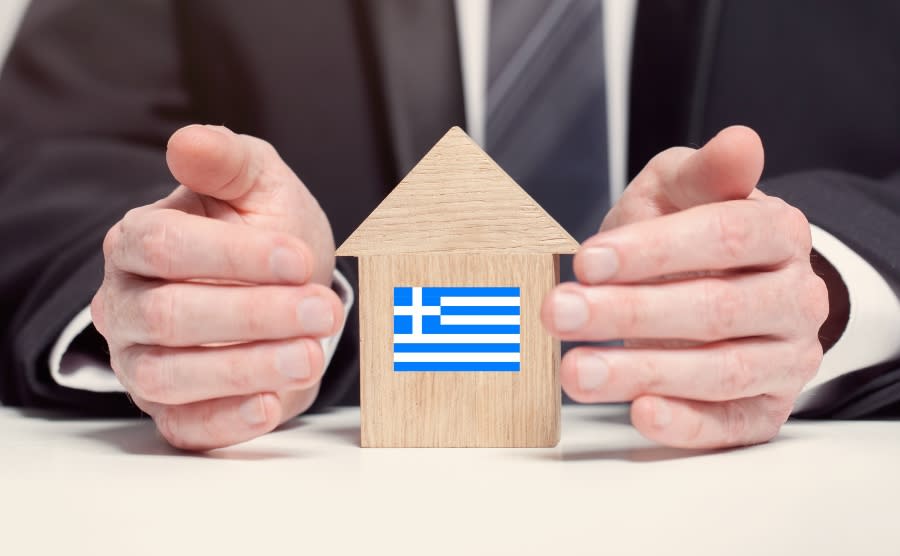 Man and wooden house with Greek flag