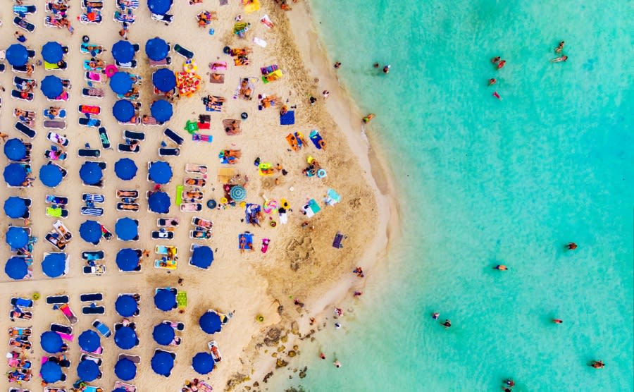 Amazing Aerial View from Above over Nissi Beach in Cyprus. Nissi Beach At high tide. Tourists relax on the beach. Crowded beach with lots of tourists. A popular place