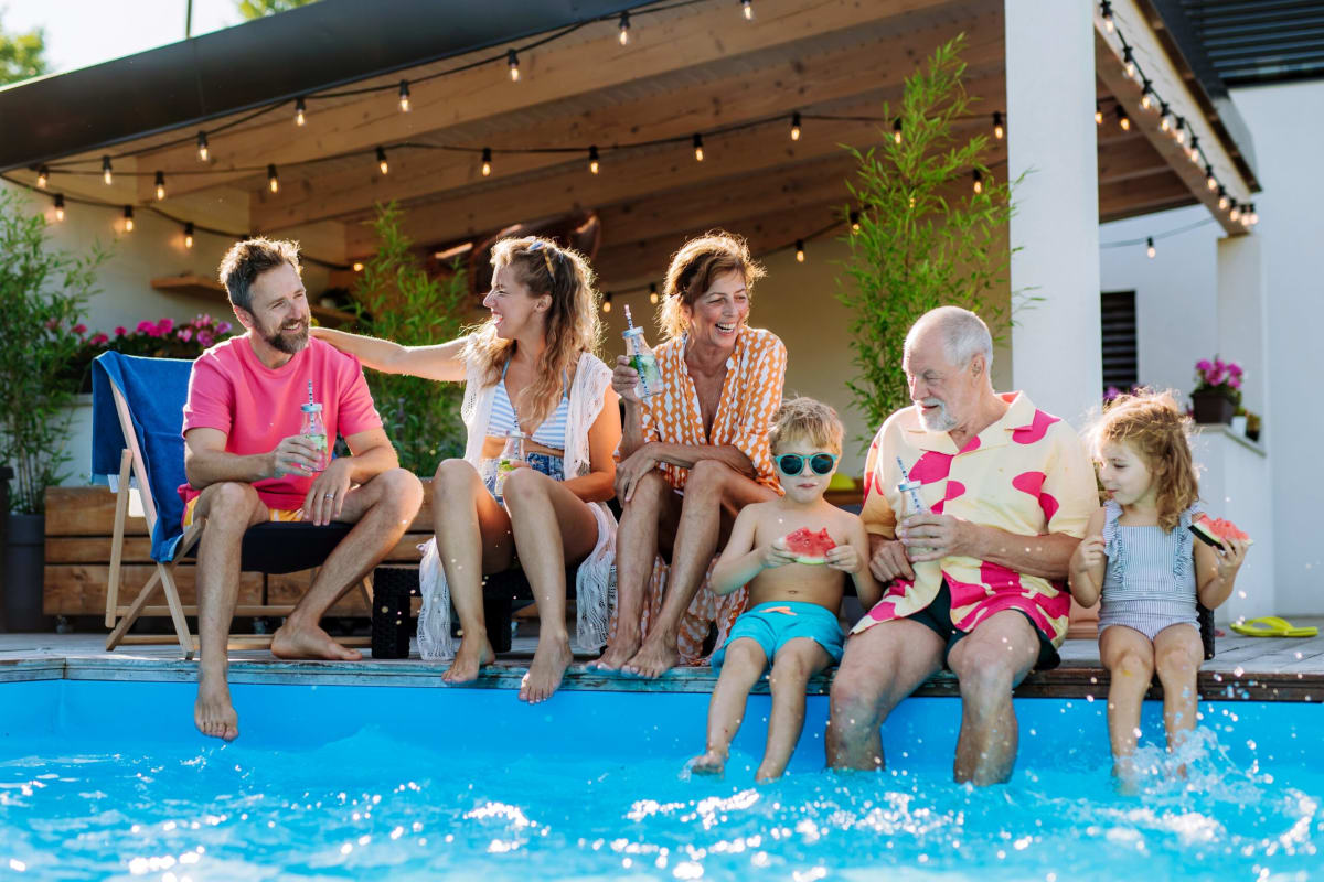 Adults and children dipping feet in swimming pool