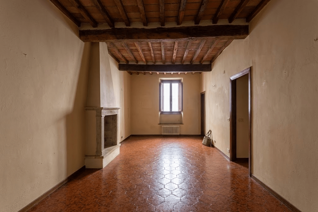 Living room before renovation, with bare walls and worn tiled floor